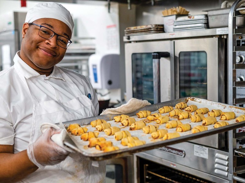 Sunflower Bakery employee with tray of baked goods.