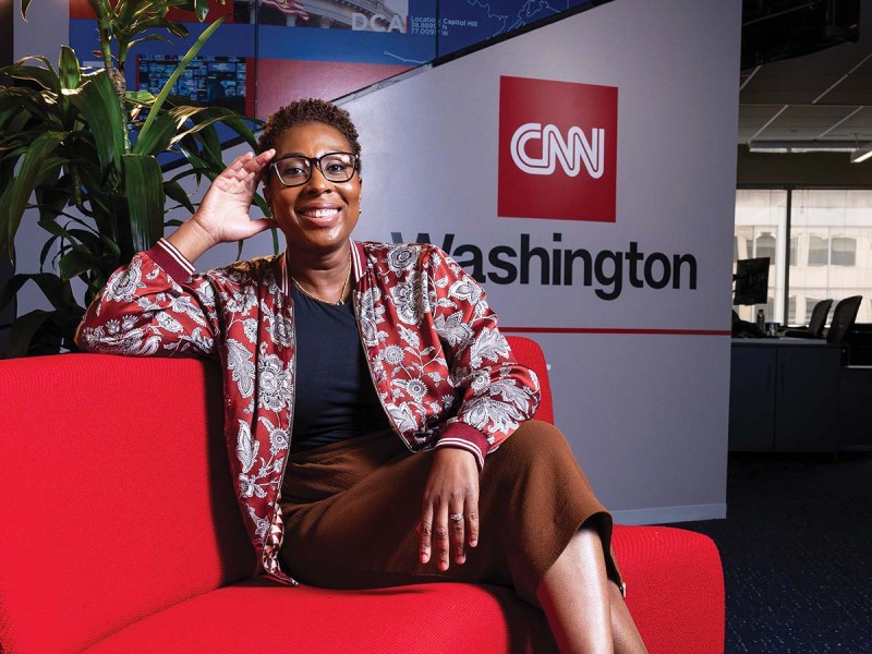 Audie Cornish at CNN's Washington, D.C., bureau sitting on a red couch. in front of a CNN Washington sign.