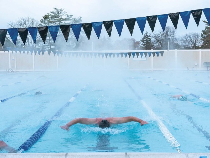 Man doing butterfly stroke in lap lane of swimming pool.