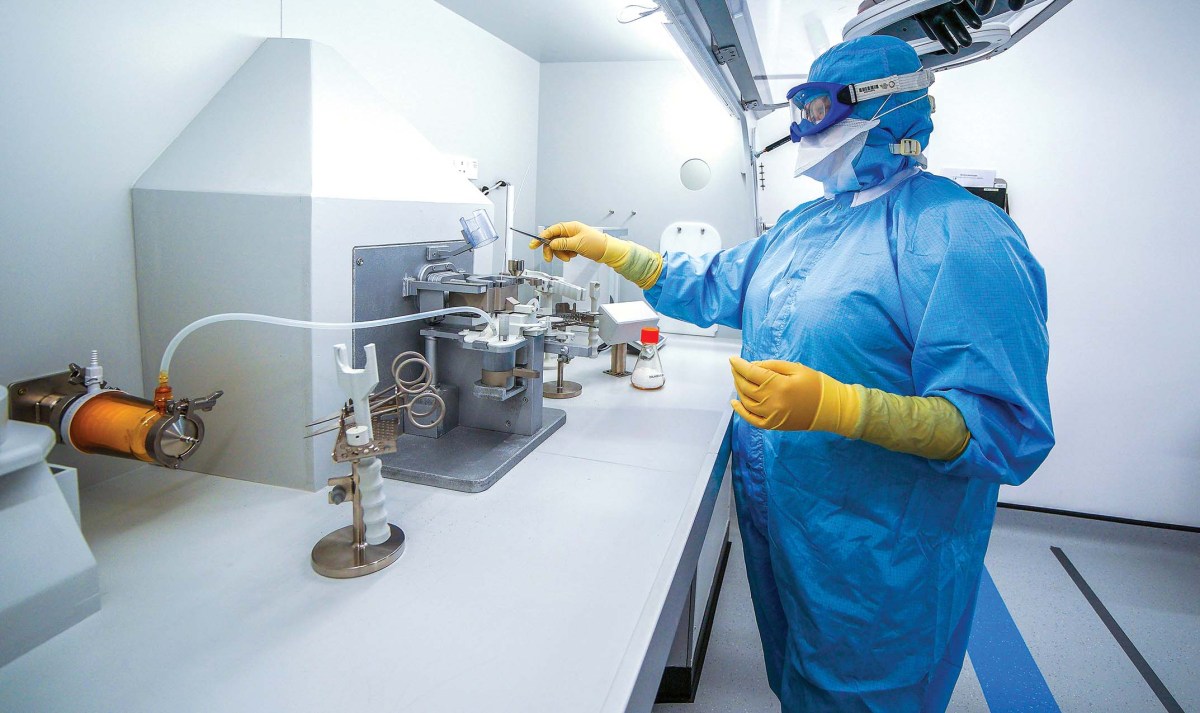 a laboratory worker in a blue suit covering their body working with equipment