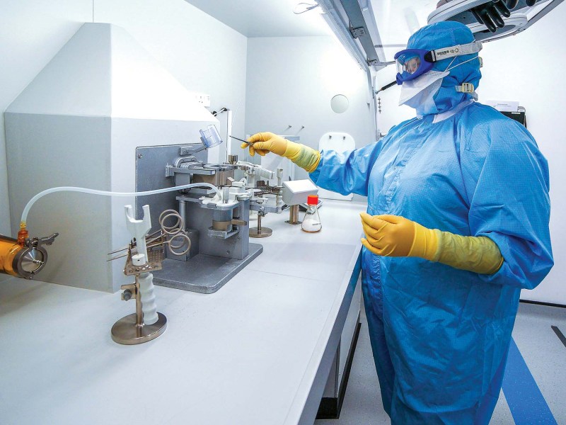 a laboratory worker in a blue suit covering their body working with equipment