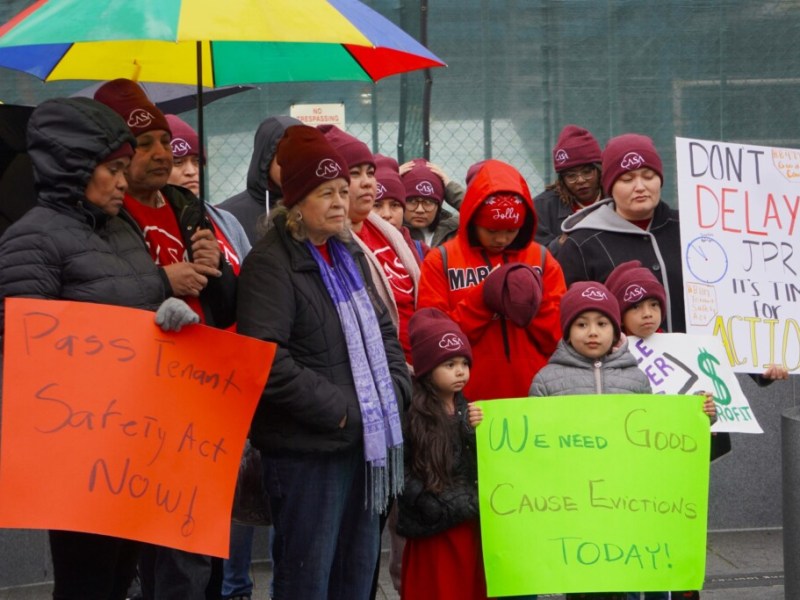 people holding signs. one says Pass Tenant Safety Act Now! and one says We need good cause evictions today!.