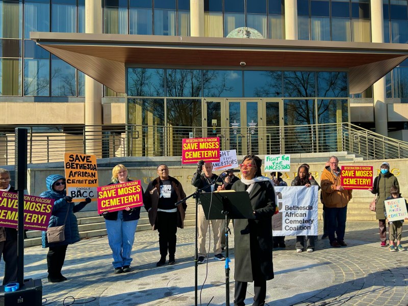 BACC President Marsha Coleman-Adebayo speaking at a press conference and rally near the steps of the Maryland Supreme Court flanked by people holding signs to save Moses Cemetary!