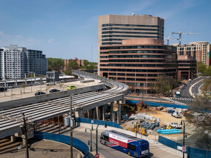 an elevated track, bus way, and buildings with visible construction