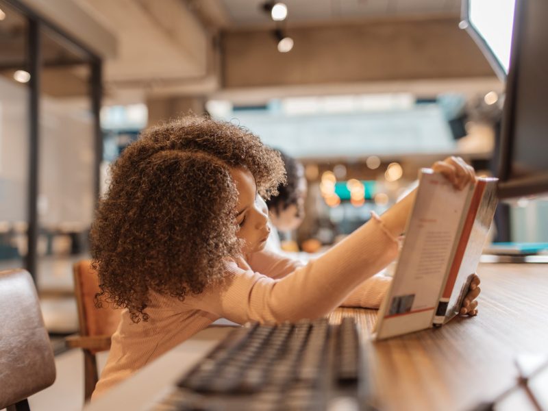 young girl reading a book in a library