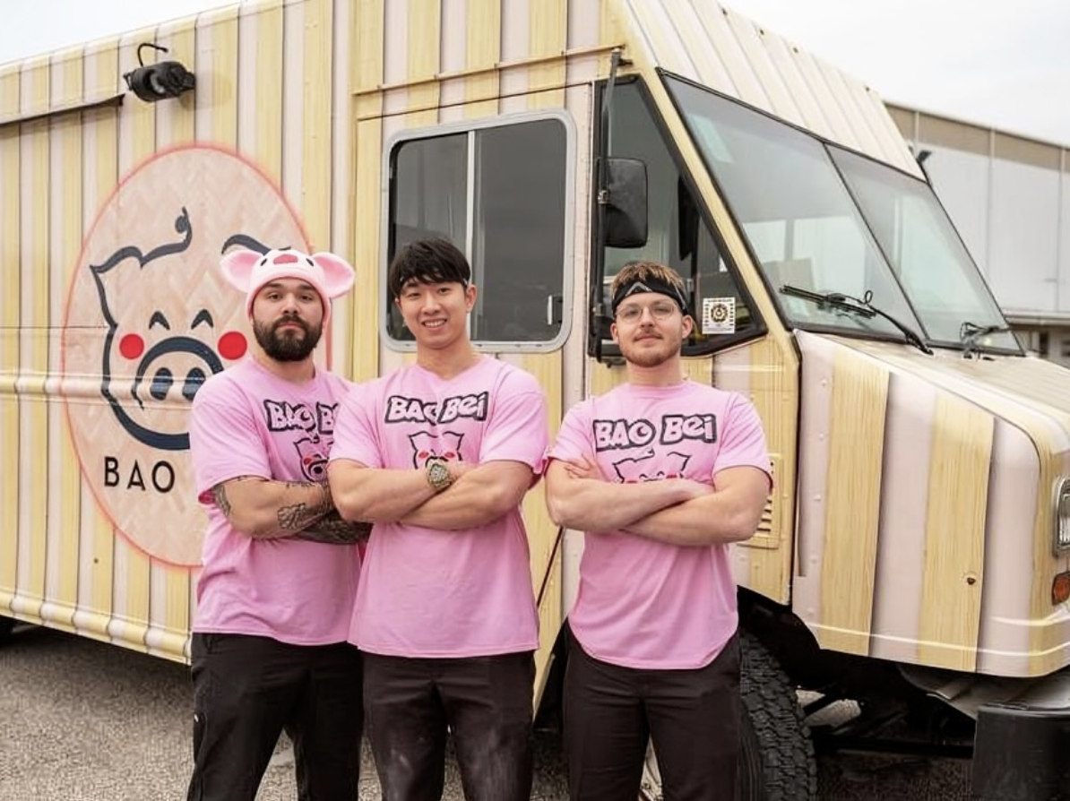 Three men in Bao Bei pink T-shirts in front of the Bao Bei truck with a pig logo